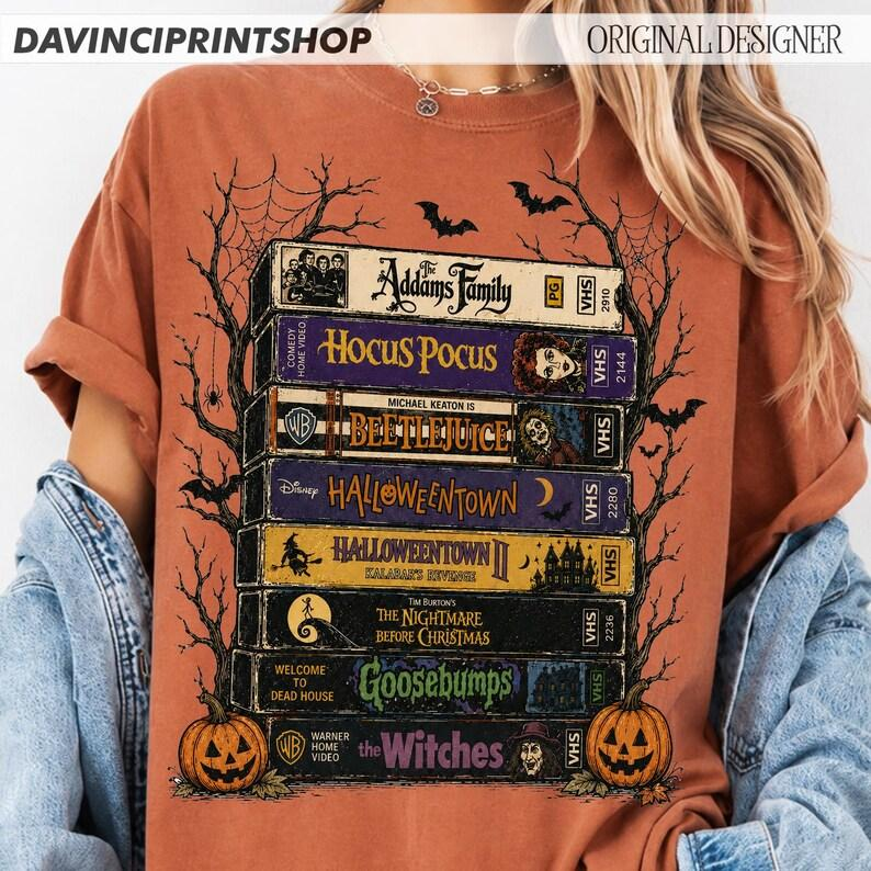 Halloween VHS Movie Stack Graphic Tee with Pumpkins, Bats, and Spooky Season Script