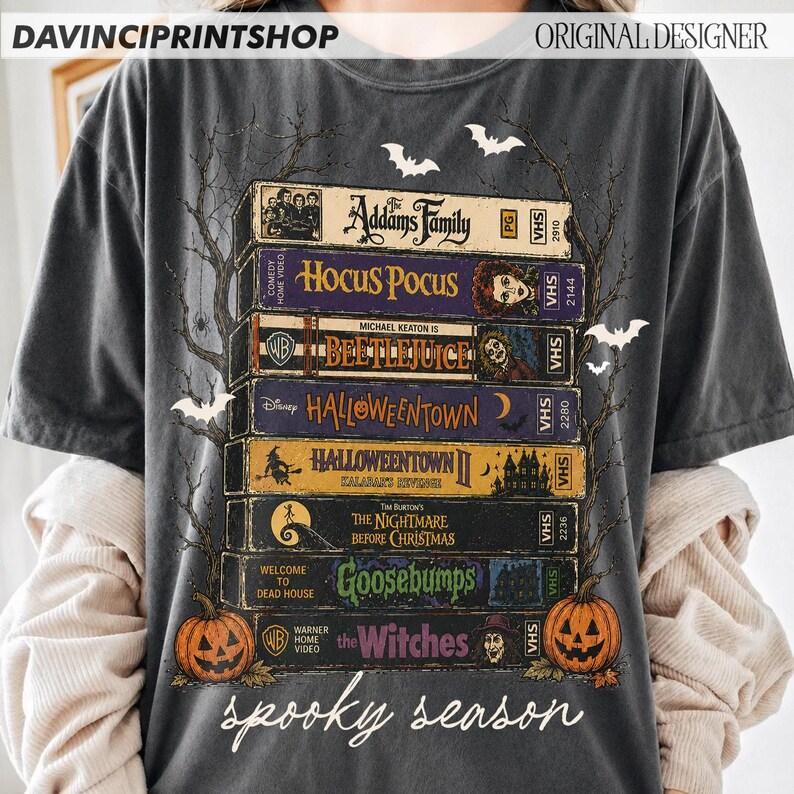 Halloween VHS Movie Stack Graphic Tee with Pumpkins, Bats, and Spooky Season Script